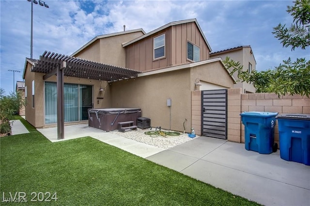 back of property with a lawn, a patio, a pergola, and a hot tub