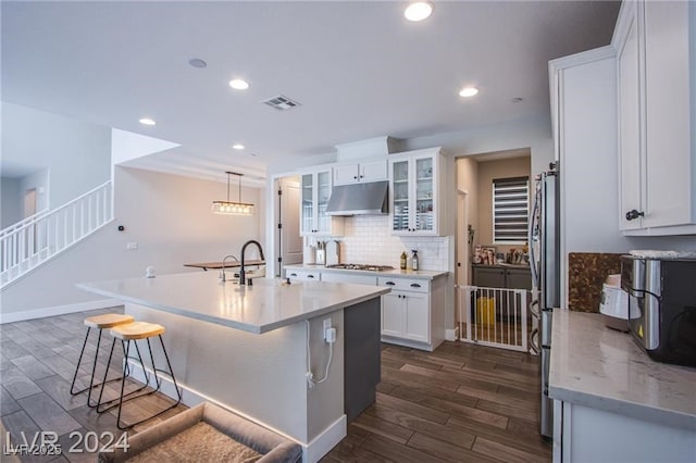 kitchen featuring white cabinetry, stainless steel appliances, dark wood-type flooring, a kitchen island with sink, and tasteful backsplash