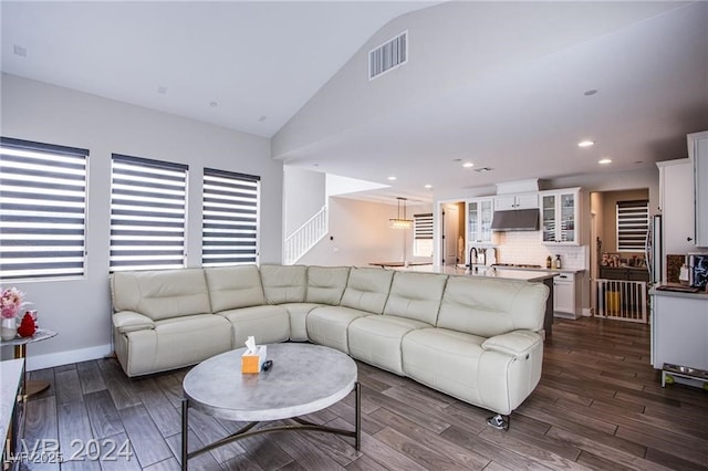 living room featuring dark hardwood / wood-style flooring, high vaulted ceiling, and sink