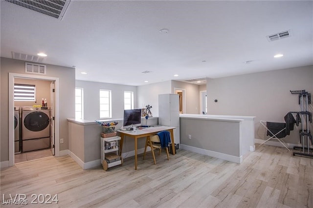 home office with light hardwood / wood-style floors and separate washer and dryer