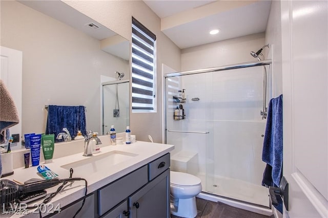 bathroom featuring hardwood / wood-style flooring, vanity, toilet, and a shower with door