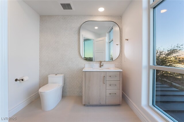 half bath featuring tile patterned flooring, toilet, vanity, visible vents, and baseboards