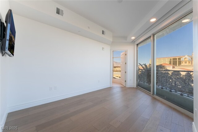 empty room with recessed lighting, wood finished floors, visible vents, and baseboards