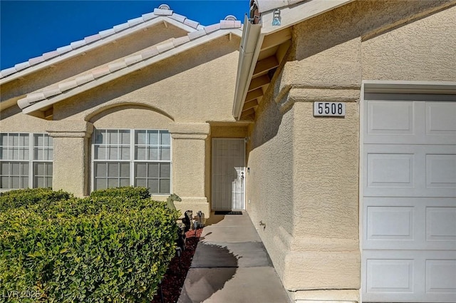 property entrance featuring a tile roof and stucco siding