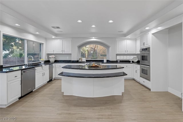 kitchen with visible vents, white cabinets, dark countertops, appliances with stainless steel finishes, and a sink