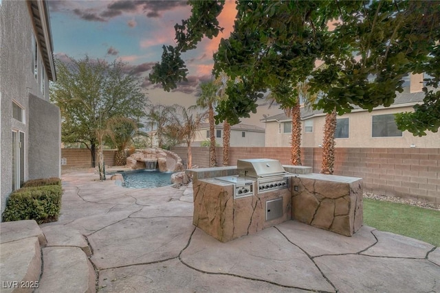 view of patio / terrace featuring exterior kitchen, a fenced backyard, and a grill