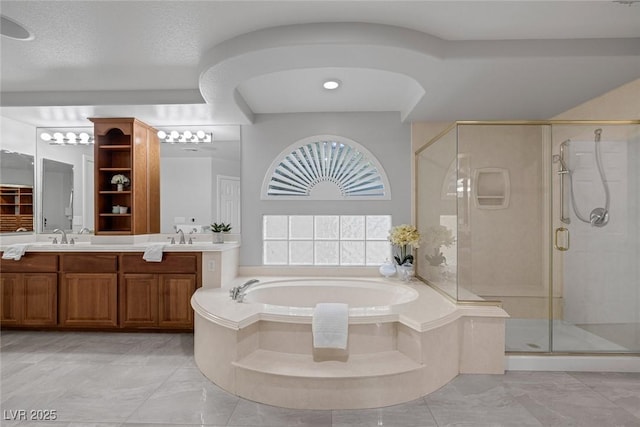 full bathroom featuring a sink, double vanity, a shower stall, and a bath