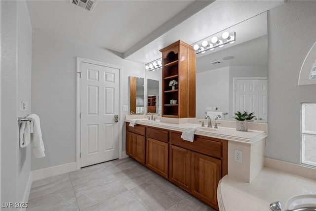 full bathroom featuring double vanity, a sink, visible vents, and baseboards