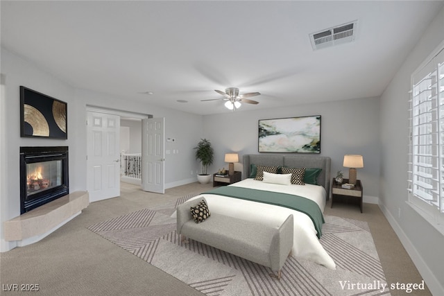 bedroom featuring light carpet, baseboards, visible vents, and a glass covered fireplace