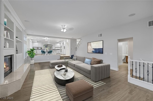 living room featuring baseboards, visible vents, dark wood finished floors, and a high end fireplace