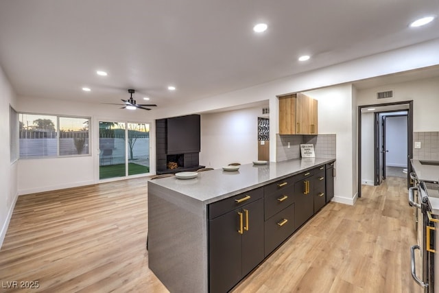 kitchen featuring kitchen peninsula, light hardwood / wood-style flooring, tasteful backsplash, ceiling fan, and light brown cabinetry