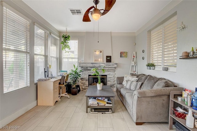 living room featuring ceiling fan and a stone fireplace