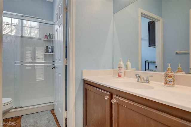 bathroom featuring toilet, vanity, and an enclosed shower