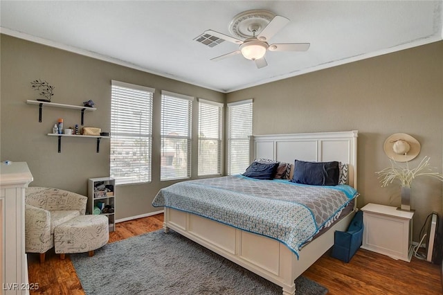 bedroom featuring dark hardwood / wood-style flooring, ornamental molding, and ceiling fan