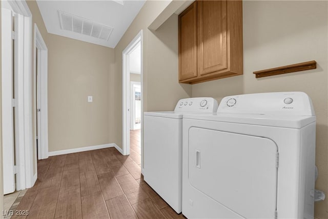 laundry room featuring cabinets, wood-type flooring, and washing machine and clothes dryer