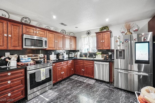 kitchen with visible vents, decorative backsplash, dark countertops, appliances with stainless steel finishes, and a sink