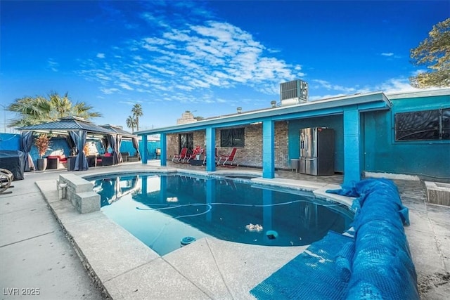 pool with cooling unit, a patio area, and a gazebo