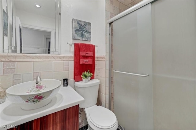 bathroom featuring a stall shower, vanity, toilet, and tile walls