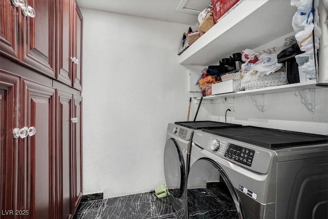 washroom with marble finish floor, washing machine and dryer, and cabinet space