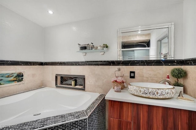 full bath with a tile shower, vanity, and a bath