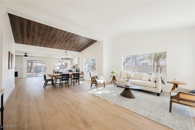 living room featuring light hardwood / wood-style floors, an inviting chandelier, and lofted ceiling