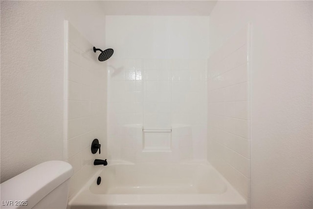 bathroom with tiled shower / bath combo and toilet