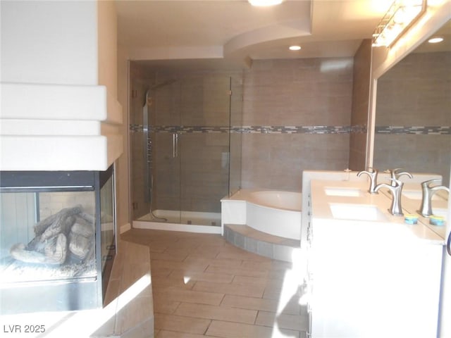 bathroom with a multi sided fireplace, vanity, tile walls, and shower with separate bathtub