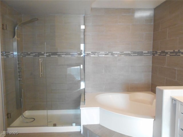 bathroom with tile walls, vanity, and shower with separate bathtub