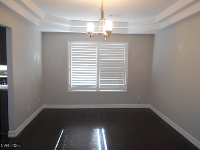 unfurnished dining area with an inviting chandelier, dark hardwood / wood-style flooring, and a raised ceiling