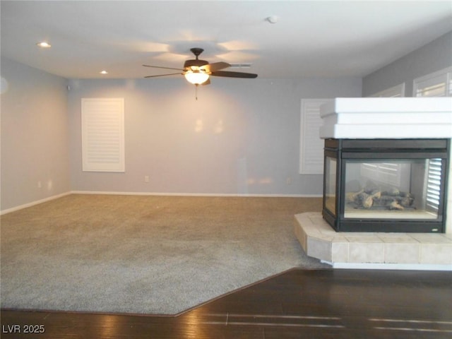 unfurnished living room with a multi sided fireplace, hardwood / wood-style flooring, and ceiling fan