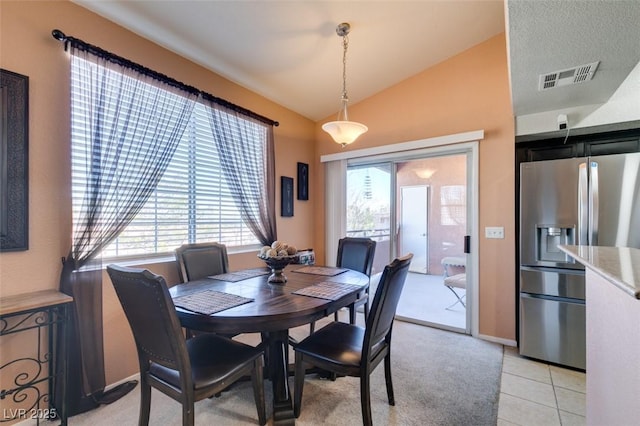 dining space featuring visible vents, vaulted ceiling, and light tile patterned floors