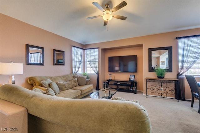 living room featuring ceiling fan, plenty of natural light, baseboards, and light colored carpet