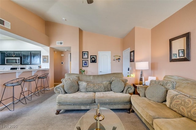 living room with carpet floors, visible vents, and vaulted ceiling