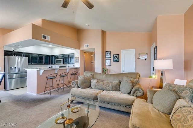 living room featuring light carpet, visible vents, high vaulted ceiling, and a ceiling fan