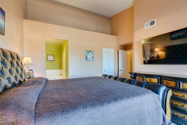 bedroom featuring ensuite bath, a high ceiling, and visible vents