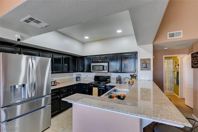 kitchen featuring stainless steel appliances, a peninsula, a sink, visible vents, and a kitchen breakfast bar