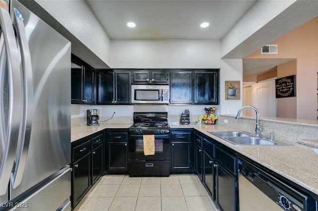 kitchen featuring light tile patterned floors, visible vents, stainless steel appliances, dark cabinetry, and a sink