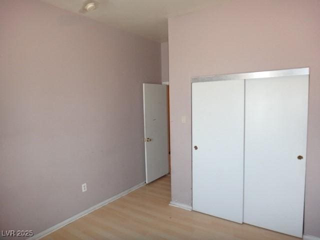 unfurnished bedroom featuring a closet, light wood-style flooring, and baseboards