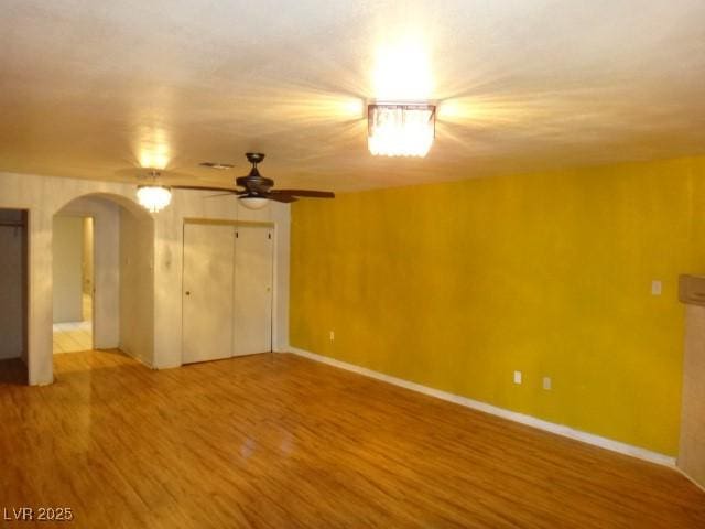 interior space with arched walkways, ceiling fan, baseboards, and wood finished floors