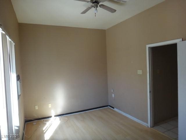 spare room featuring ceiling fan, light wood-type flooring, and baseboards