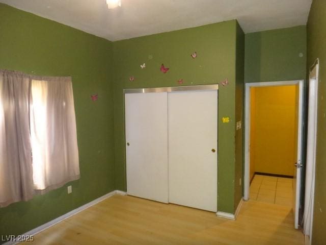 unfurnished bedroom with a closet, wood finished floors, and baseboards