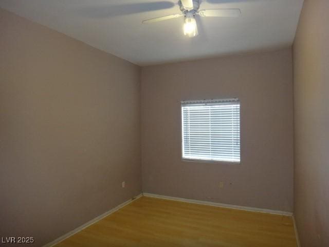 spare room featuring a ceiling fan, baseboards, and light wood finished floors