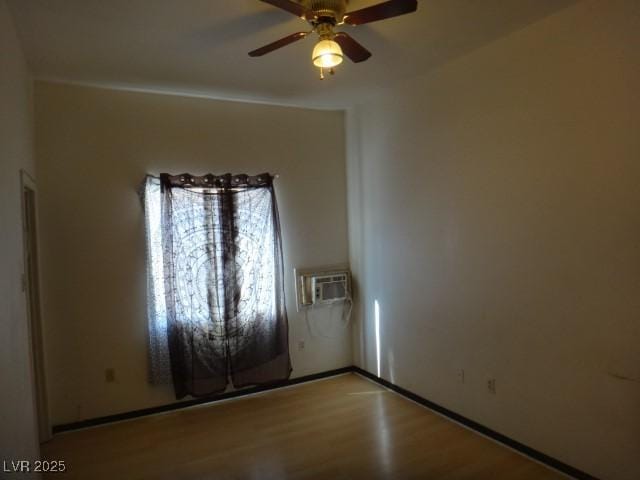 unfurnished room with a wall unit AC, ceiling fan, and wood finished floors