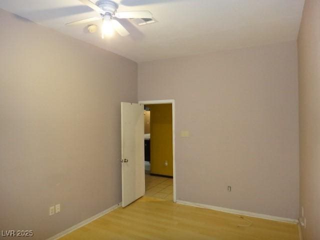 empty room with baseboards, ceiling fan, and light wood finished floors