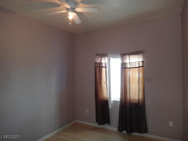 empty room featuring light wood-style flooring, a ceiling fan, and baseboards