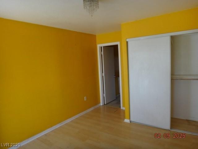 unfurnished bedroom featuring a closet, baseboards, and wood finished floors