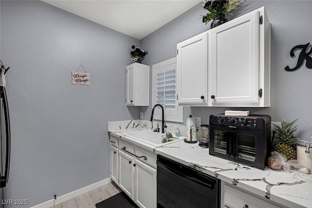 kitchen featuring white cabinetry, dishwashing machine, light stone countertops, light hardwood / wood-style floors, and sink