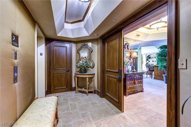 foyer featuring stone finish flooring, ornamental molding, a raised ceiling, and visible vents