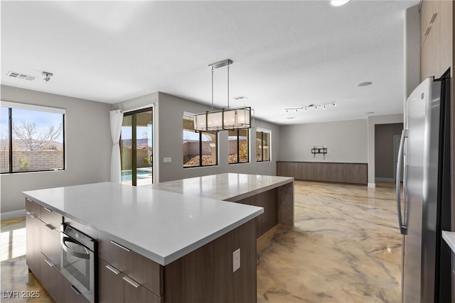 kitchen with a spacious island, light countertops, visible vents, freestanding refrigerator, and modern cabinets