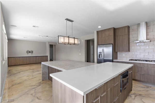 kitchen with decorative backsplash, a spacious island, wall chimney exhaust hood, modern cabinets, and stainless steel appliances